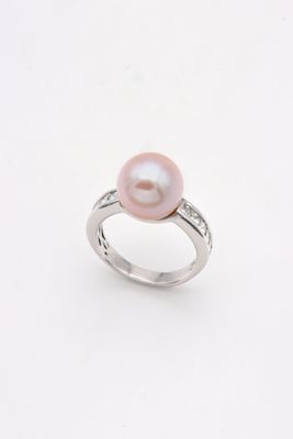 une bague en perle rose et diamants sur fond blanc