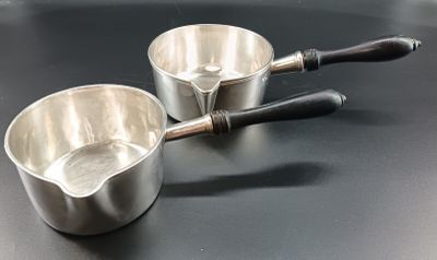 two metal bowls on a black table with a wooden handle