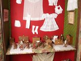 une maison de poupées avec des vêtements posés sur une étagère dans un coin