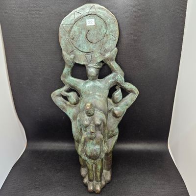 statue en bronze représentant un homme tenant une pièce de monnaie sur la tête