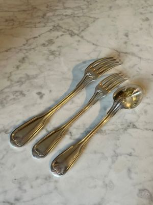 three forks and a spoon on a marble table