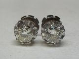 une paire de boucles d'oreilles à clous en diamant posées sur une surface blanche