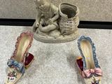 une petite statue représentant un bébé assis à côté d'une paire de chaussures