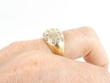 a man ' s hand holding a gold ring with diamonds on it