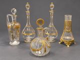 cinq vases en verre ornés de motifs dorés, posés sur une table