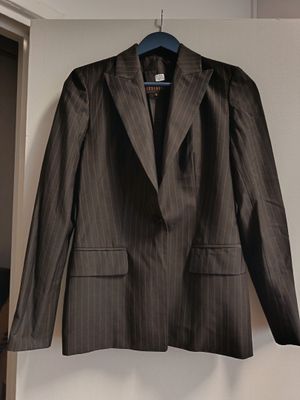 une veste de costume marron à fines rayures suspendue à un cintre dans une pièce