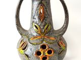 un vase gris orné de fleurs orange sur un fond blanc