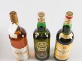 three bottles of alcohol are sitting next to each other on a white surface