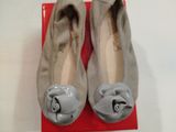 une paire de chaussures grises ornées de nœuds, posée sur une boîte rouge