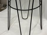 black metal stool with a glass top on a white background