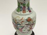 a vase with a lid on a stand on a white surface