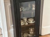 une armoire noire avec une porte vitrée, dans un coin de la pièce