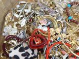 a wooden bowl filled with lots of jewelry on a table