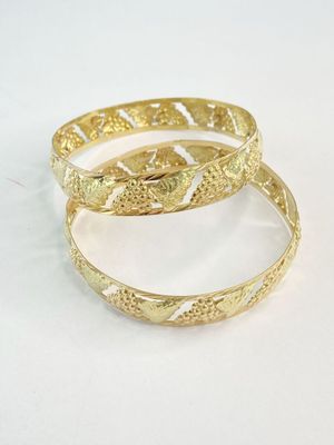 deux bracelets rigides en or posés sur une surface blanche