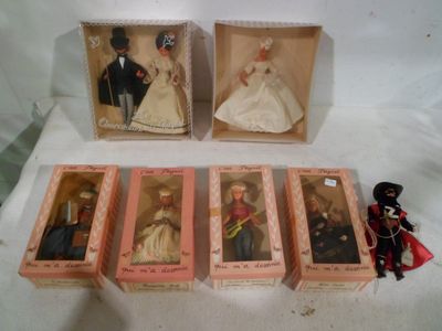six boxed dolls of different styles and sizes in boxes on a white surface