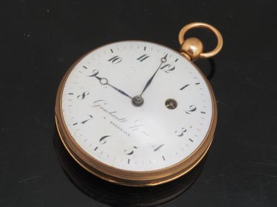 un gros plan d'une montre de poche en or posée sur une table