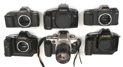 several cameras are lined up on a white surface with a strap around them