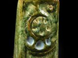 un vase vert orné d'un motif sur fond noir