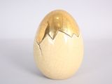 a golden egg with a broken shell on a white surface