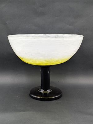 a white and yellow bowl sitting on top of a black base
