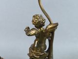 an antique brass table lamp with a cupid holding a candle