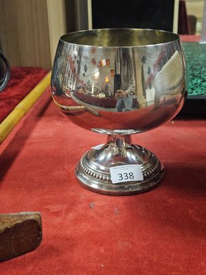 a silver goblet on a red table with a piece of bread in the background