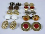several pairs of earrings and rings are sitting on a white surface
