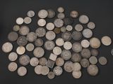 a pile of old silver coins on a black surface