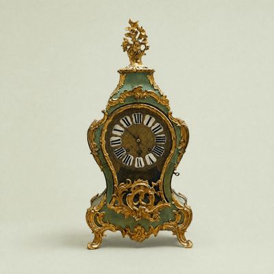 a green and gold clock sitting on a white surface