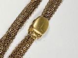 two gold chains with a gold skull charm on a white surface
