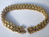 a close up of a gold bracelet on a white surface