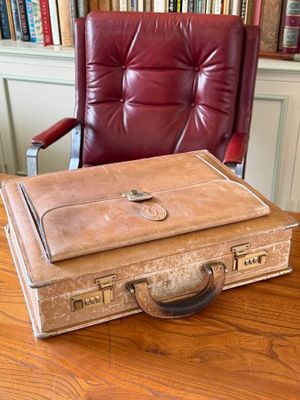 a brown suitcase sitting on a wooden table in front of a red chair