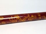 a red cylinder with gold designs on it sitting on a white surface