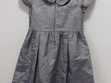 a little girl ' s dress hanging on a hanger against a wall