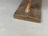 bronze statue of a man with a hat and a cane on a base
