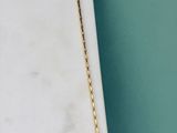 un collier en or avec une longue chaîne posé sur une dalle de marbre