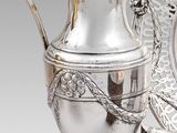 un pichet en argent et une assiette en argent placés l'un à côté de l'autre