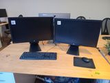 two computer monitors sitting on a desk with a keyboard and mouse