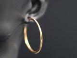 un gros plan sur des boucles d'oreilles créoles en or sur une tête de mannequin