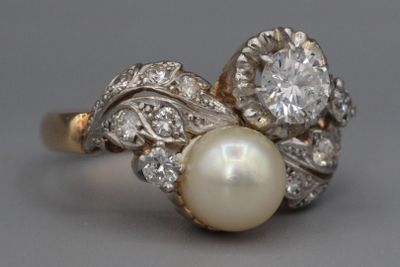 une photo d'une bague en perle et diamant posée sur une table