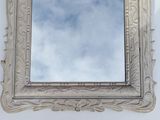 a mirror hanging on a wall with a sky in the background