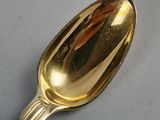 a gold spoon on a white surface with a reflection of a building