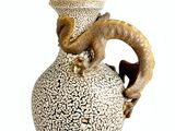 a white vase with a brown handle and a ram head on it