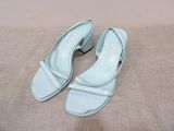 une paire de chaussures bleu clair posée sur un lit, sur fond beige