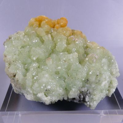 un petit morceau de minéral vert et jaune posé sur une assiette transparente