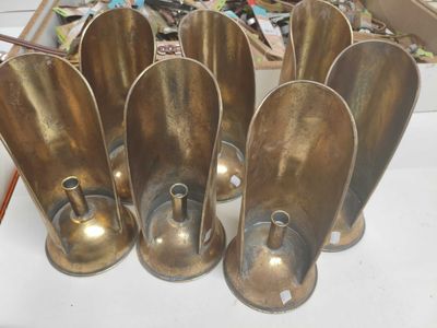 cinq cuillères en laiton posées sur une table devant un tas de bric-à-brac