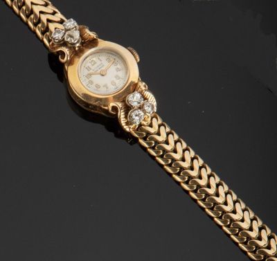 Gros plan sur une montre-bracelet en or entourée d'une chaîne