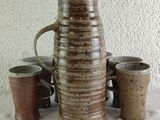 a vase and cups sitting on a table next to each other