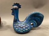 a blue rooster figurine next to an orange