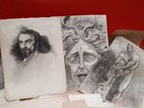 a pile of drawings on a table with a red wall in the background